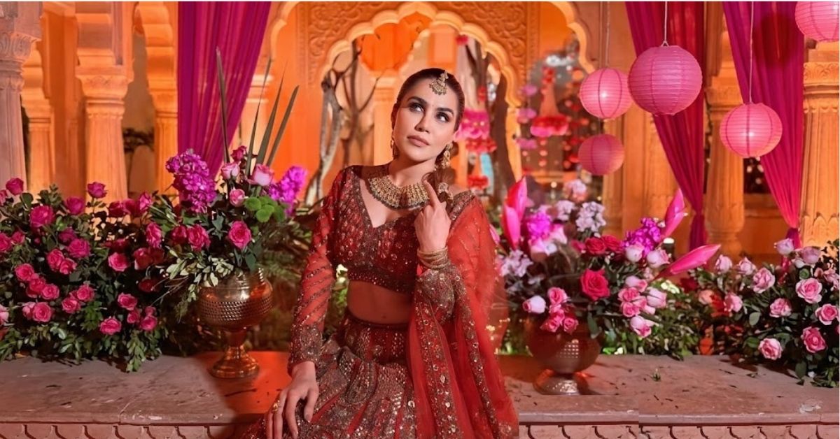 Bhawna chandani in traditional red attire with floral decorations and pink lanterns in the background