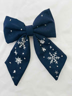 Navy blue bow with white snowflake patterns on a light gray background