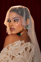 A women in photo studio lighting wearing white gown and micro veil and green choker