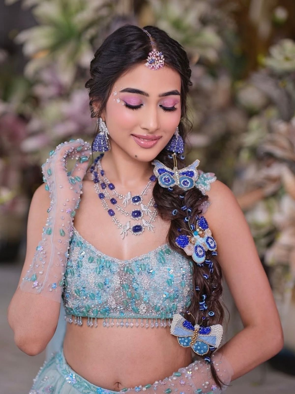 Model in traditional attire with jewelry and evil eye and butterflies by loveknots in braided hair