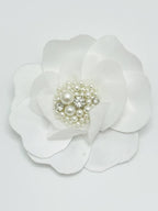 White flower hair clip with pearl and crystal center on a light gray background