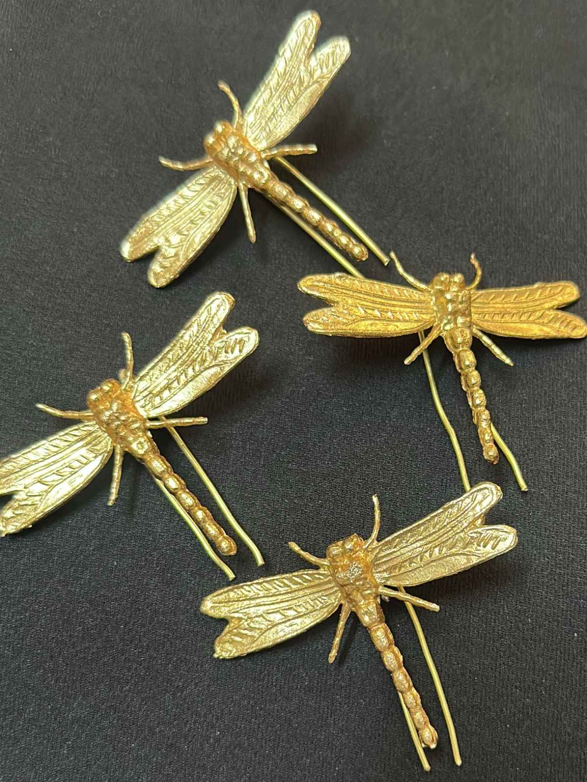 Gold dragonfly-shaped pins on a black background