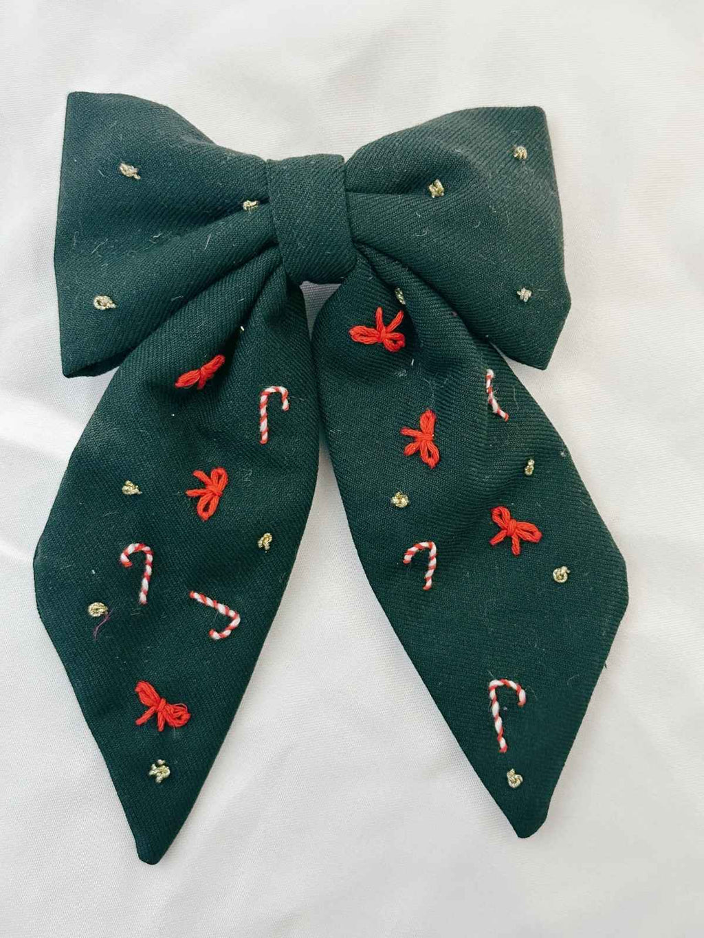 Green bow with embroidered candy cane and bow designs on a white background