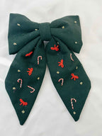 Green bow with embroidered candy cane and bow designs on a white background