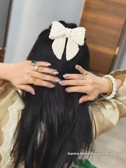 celebrity kanica Maheshwari wearing a decorative pearl aria hair bow by loveknots with hands holding the hair, against a neutral background.