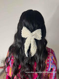 Woman with long, wavy hair wearing a decorative pearl Amara bow hair accessory against a neutral background, styled by influencer Paawni Behl
