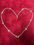 Pearl and ghungroo tassel hair chain lying in heart shape on red background