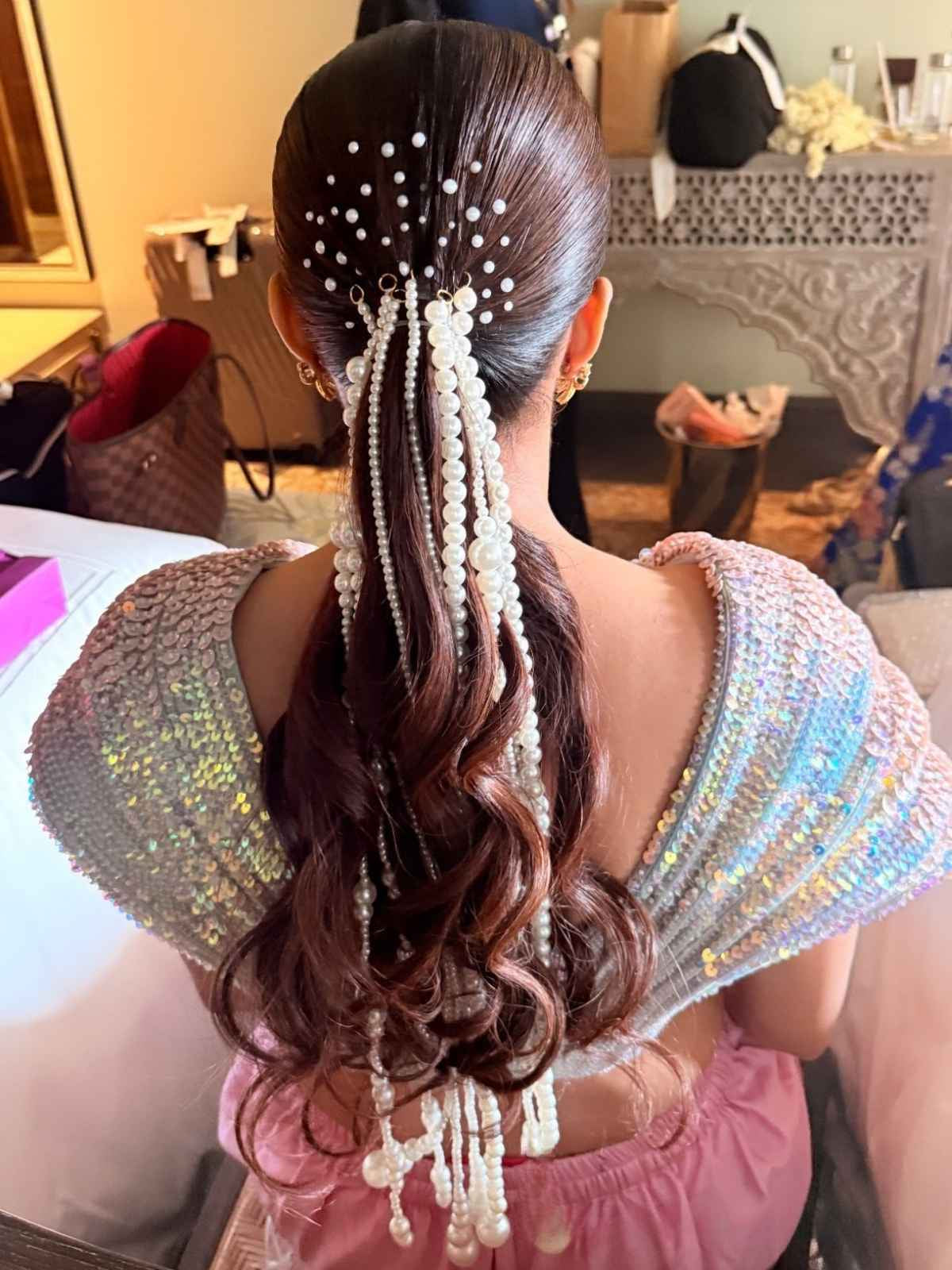 Woman with elaborate hairdo featuring pearls in a room setting
