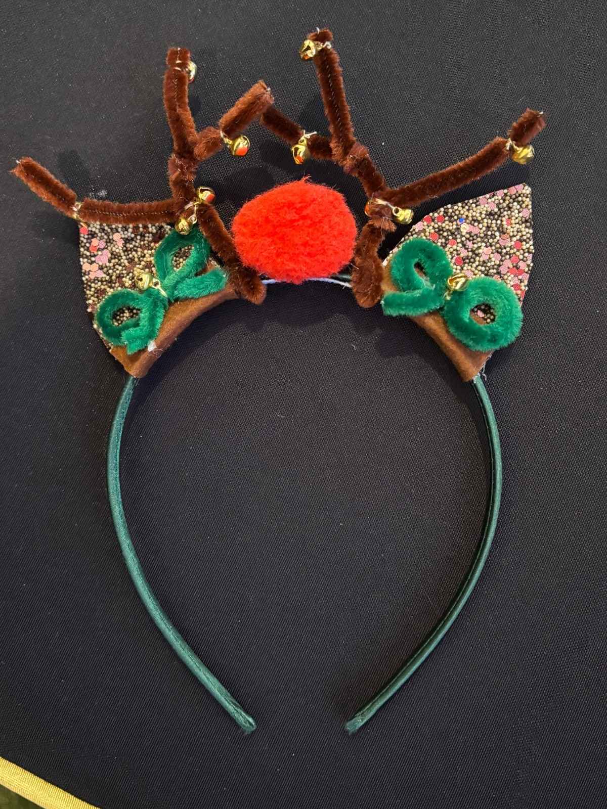Decorative reindeer headband with antlers, a nose, and ears on a black background