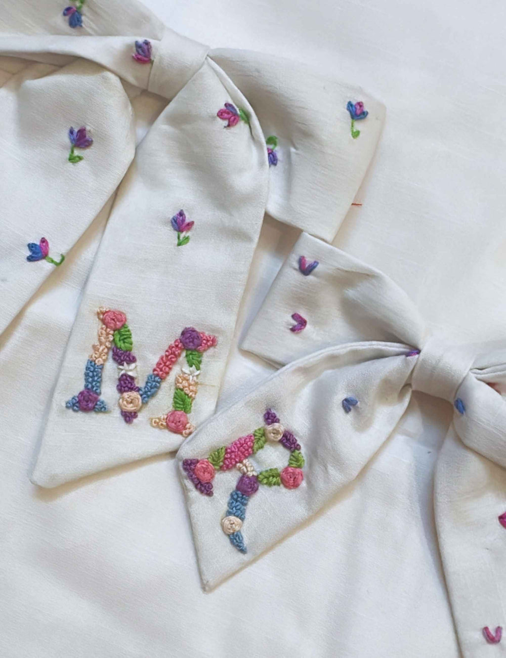 Embroidered fabric with colorful letters and floral patterns on a white background