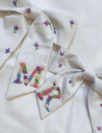 Embroidered fabric with colorful letters and floral patterns on a white background