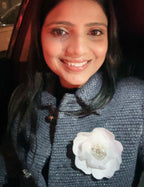 Woman wearing a dark blue jacket with a white handmade dhalia flower accessory by loveknots