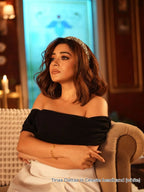 Tinaa Datta wearing a black off-shoulder top with a crystal headband by loveknots, sitting on a couch.