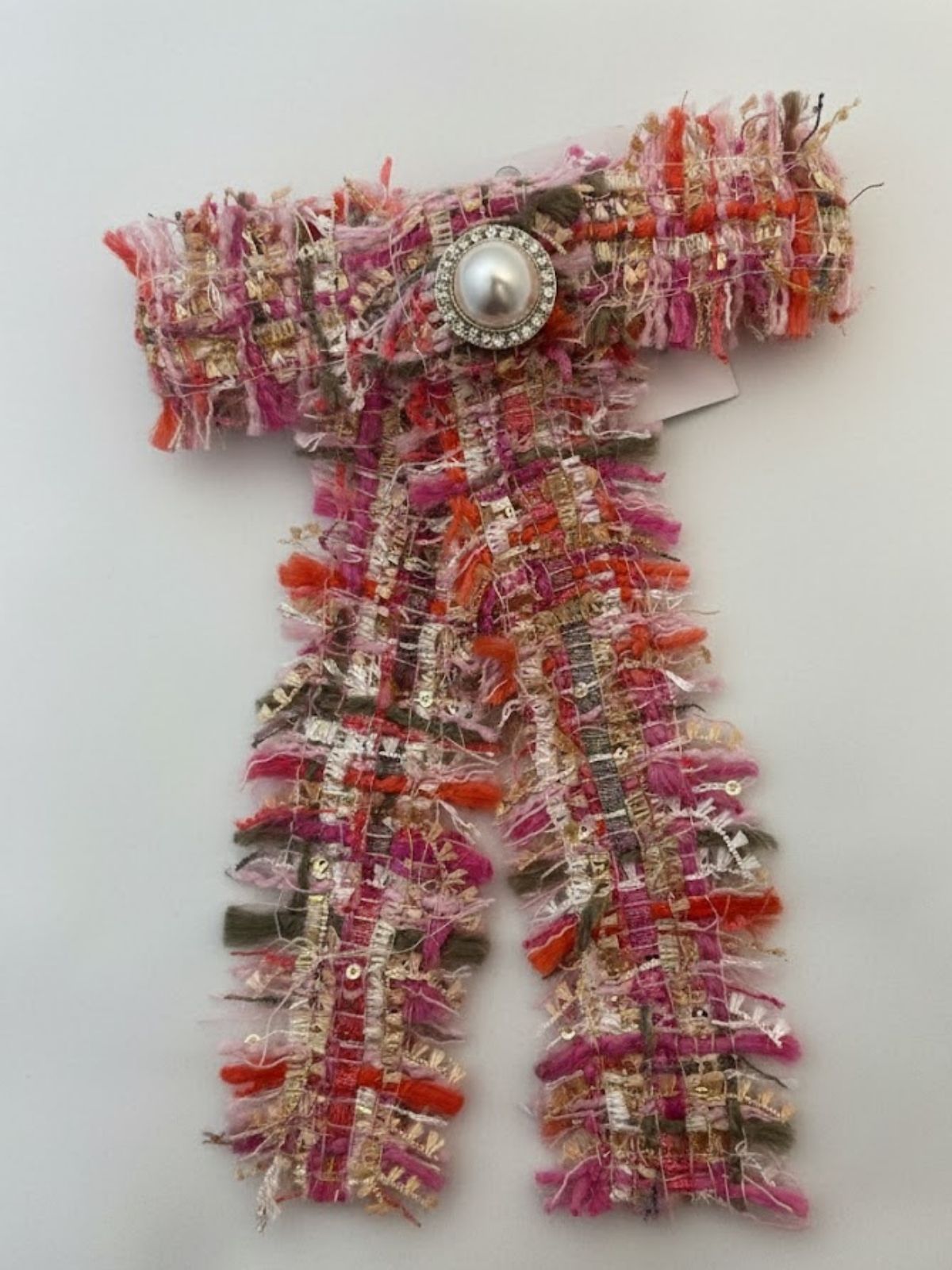 Pink Tweed bow with fringed edgeswith a decorative button on a white background