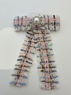 Tweed bow pink n blue with a pearl center on a white background