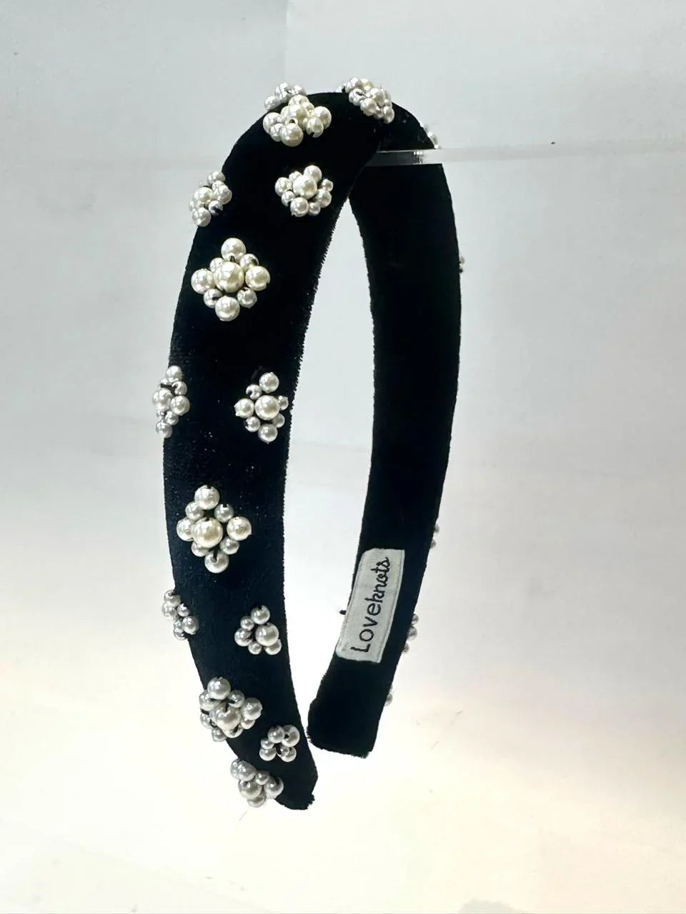 black velvet hairband with pearl embellishments on a white background