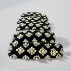 Set of black hair clips with white pearl embellishments on a light gray background