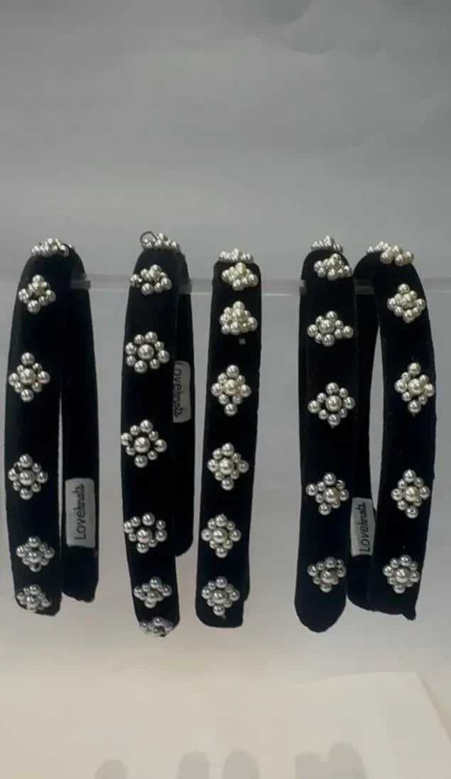 Set of black hairbands with white pearl floral designs on a white background