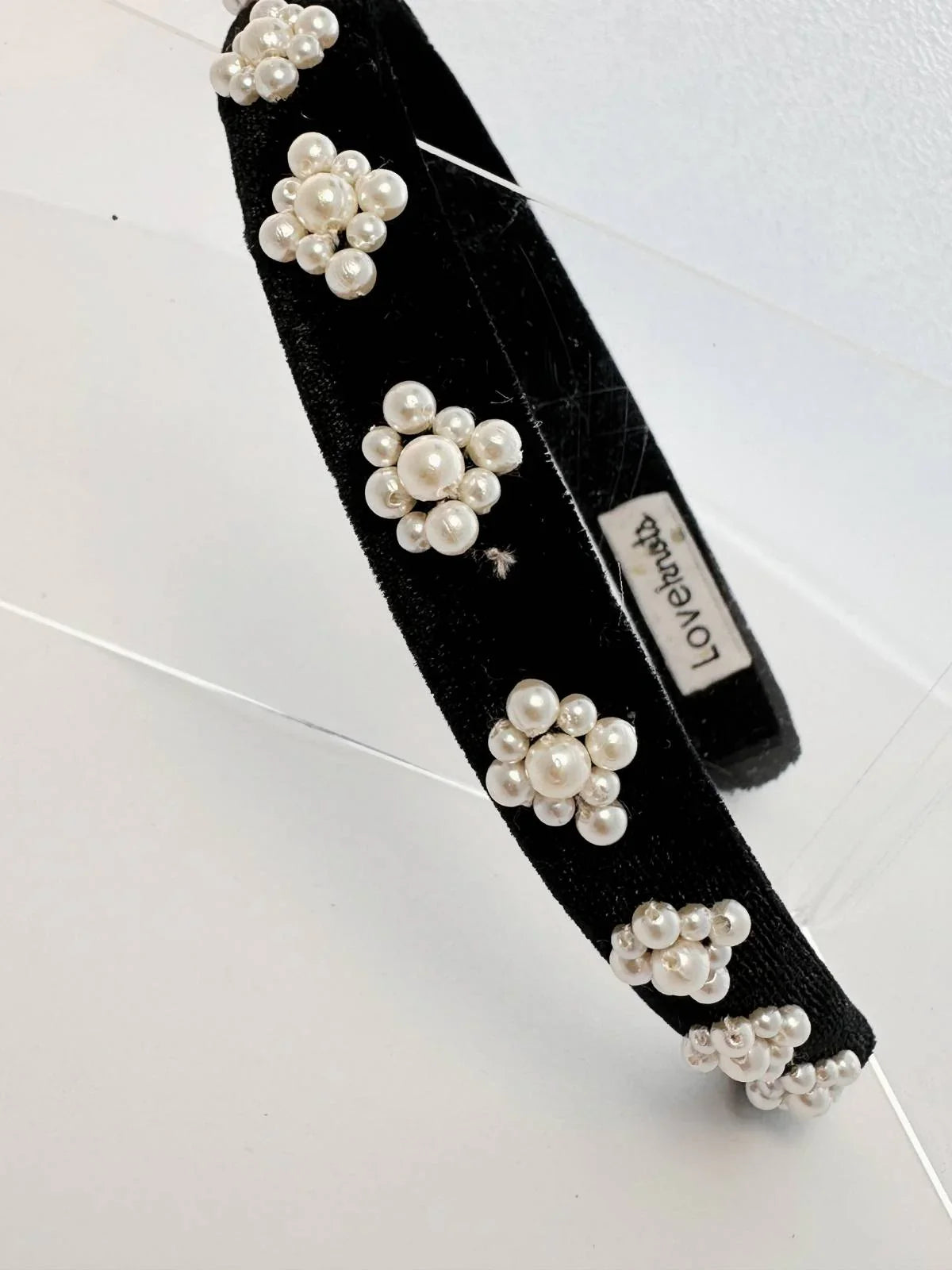 Black headband with pearl embellishments on a white background