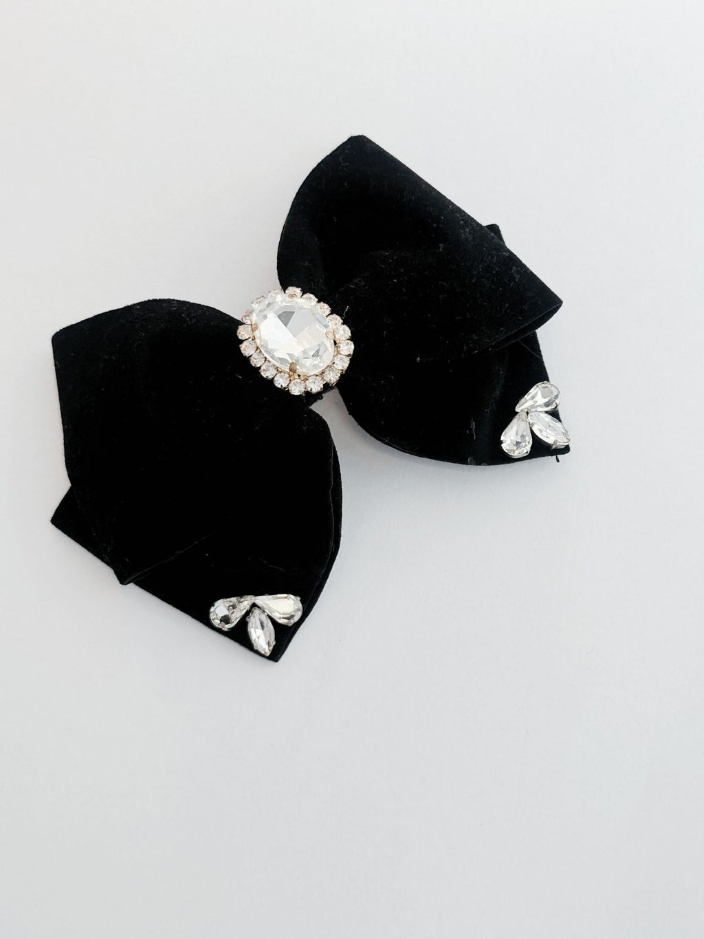 Black bow hair clip with crystal embellishments on a light gray background
