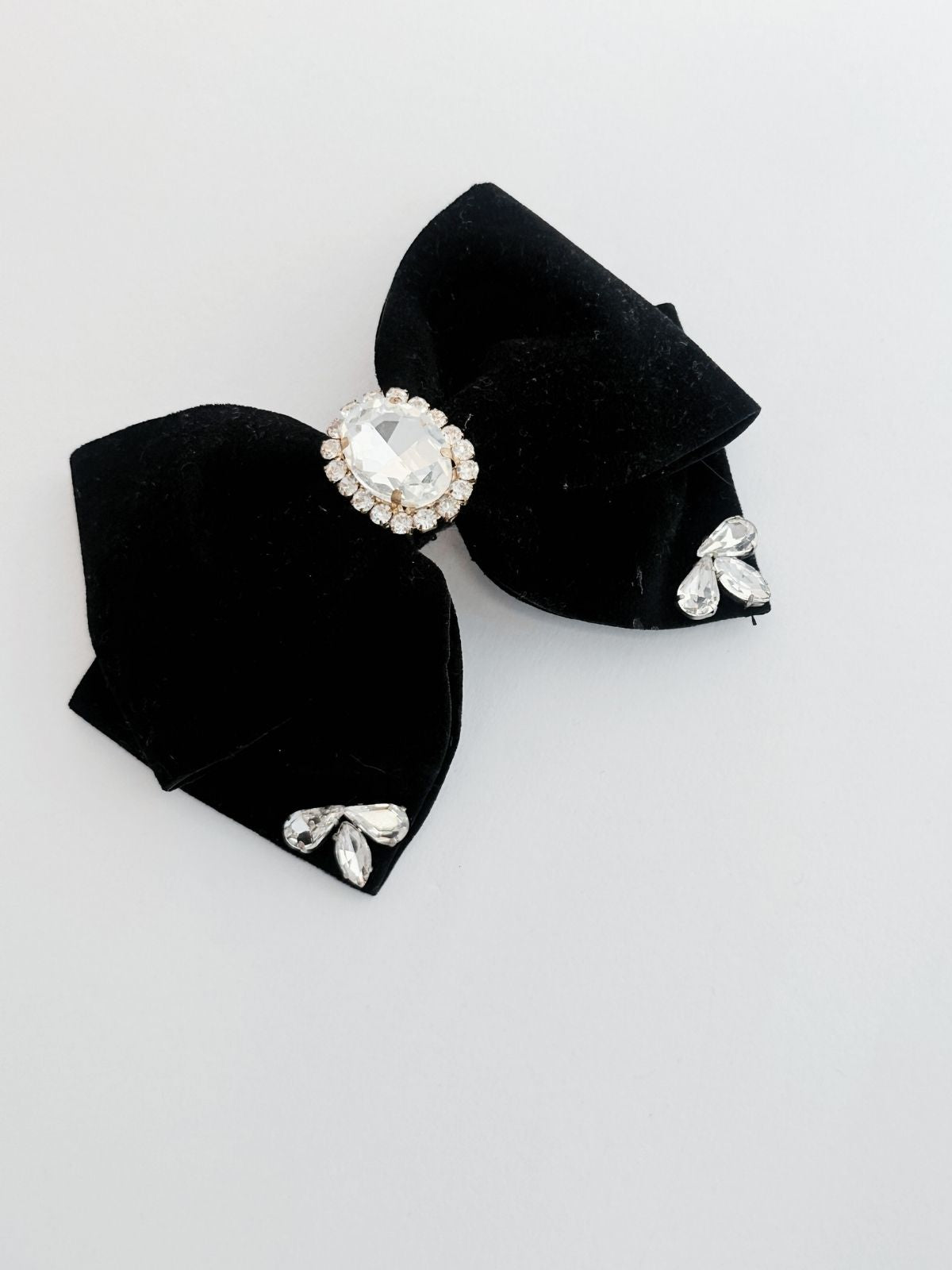 Black bow hair clip with crystal embellishments on a light gray background