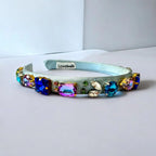 blue jeweled headband on a white surface with a light gray background