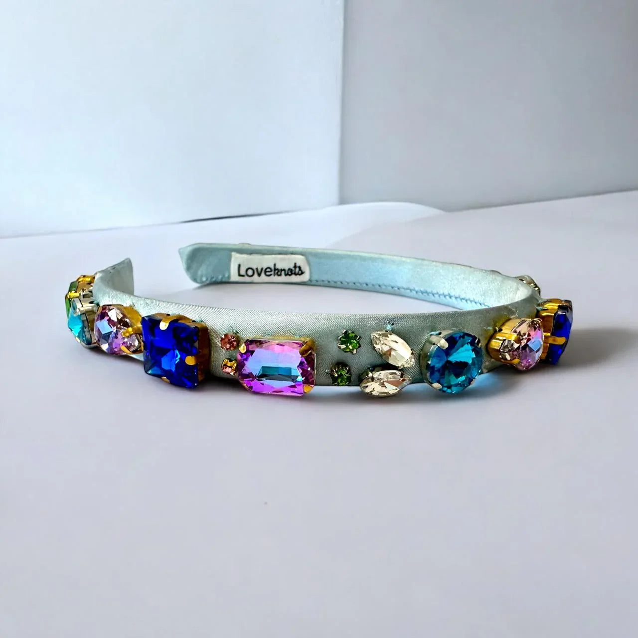 blue jeweled headband on a white surface with a light gray background