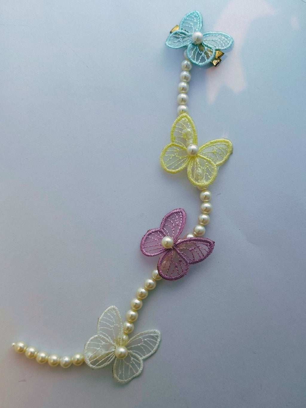 Decorative string with butterflies and pearls on a light gray background