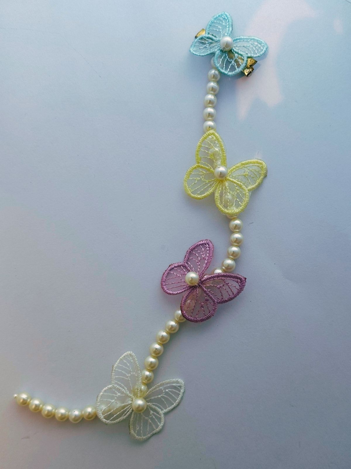 Decorative string with butterflies and pearls on a light gray background