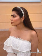 celebrity influencer Bhavna Chandni wearing a white off-shoulder top with a decorative headband against a beige wall in Disney land in usa.