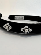 Black headband with white floral pearl embellishments on a white background