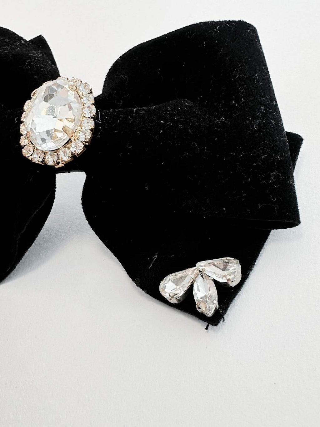 Black bow hair clip with crystal embellishments on a white background