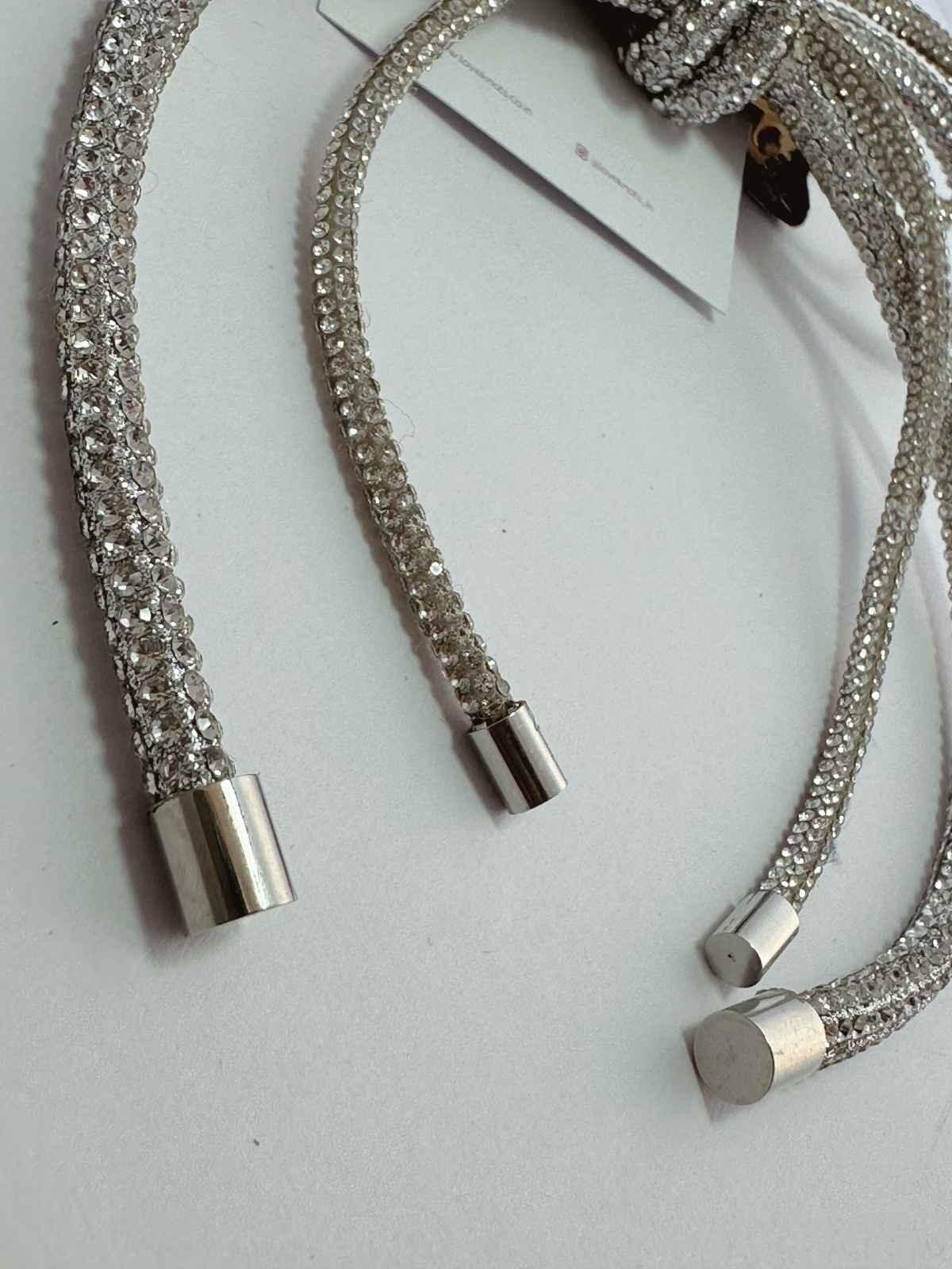 Silver crystal bow with metal clasps on a light gray background