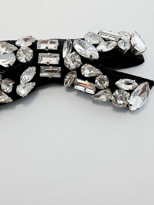 Black bow tie with crystal embellishments on a light gray background