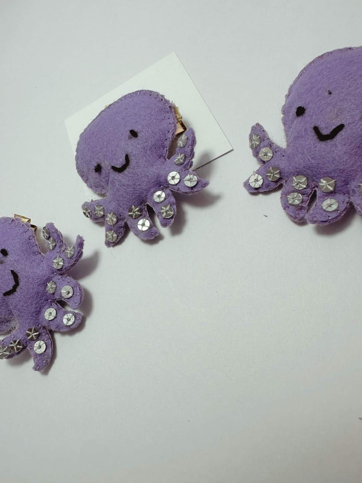 Purple octopus-shaped embellished hair clip on a white card with 'loveknots' branding.