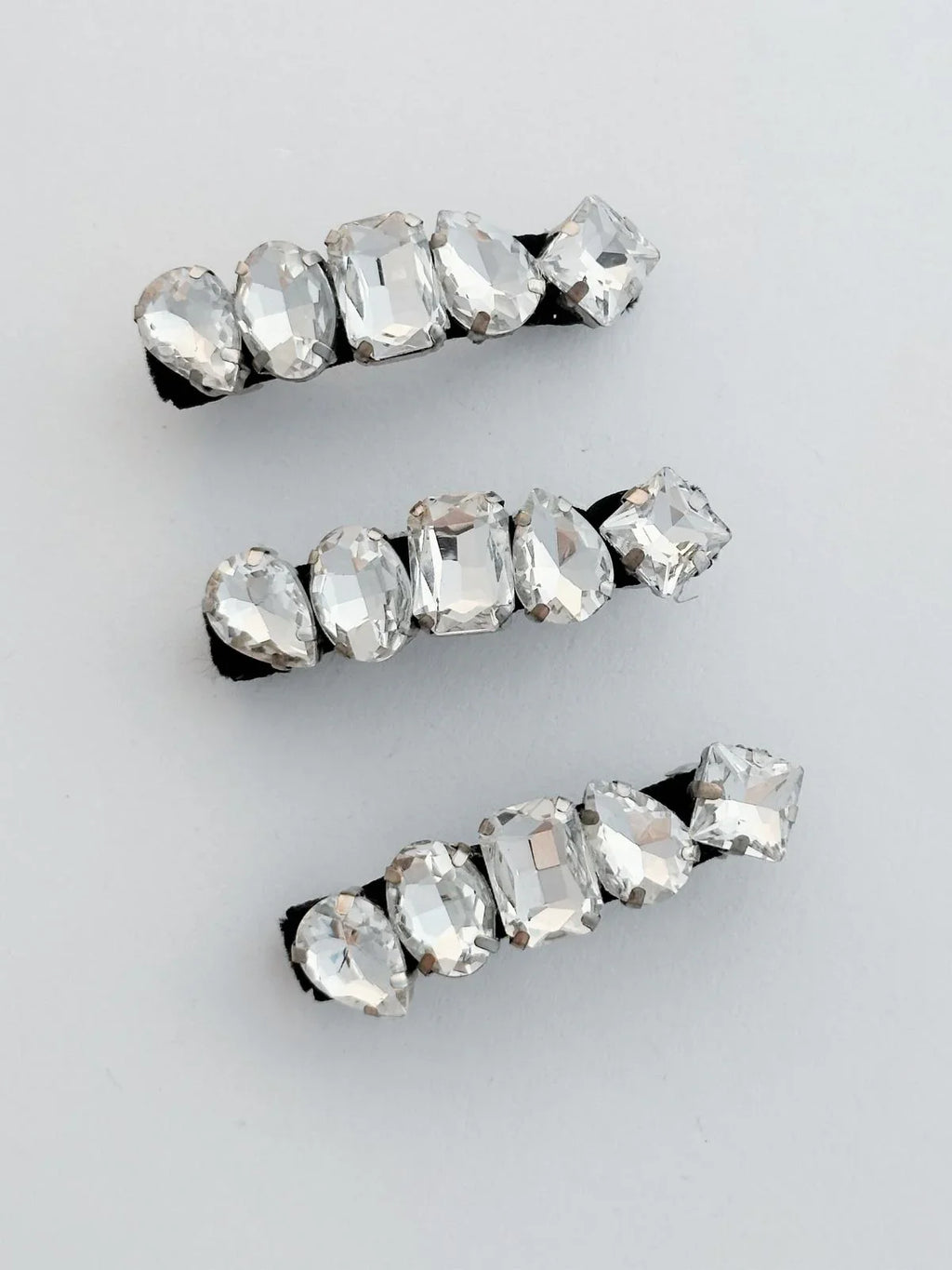 Set of three crystal hair clips on a light gray background