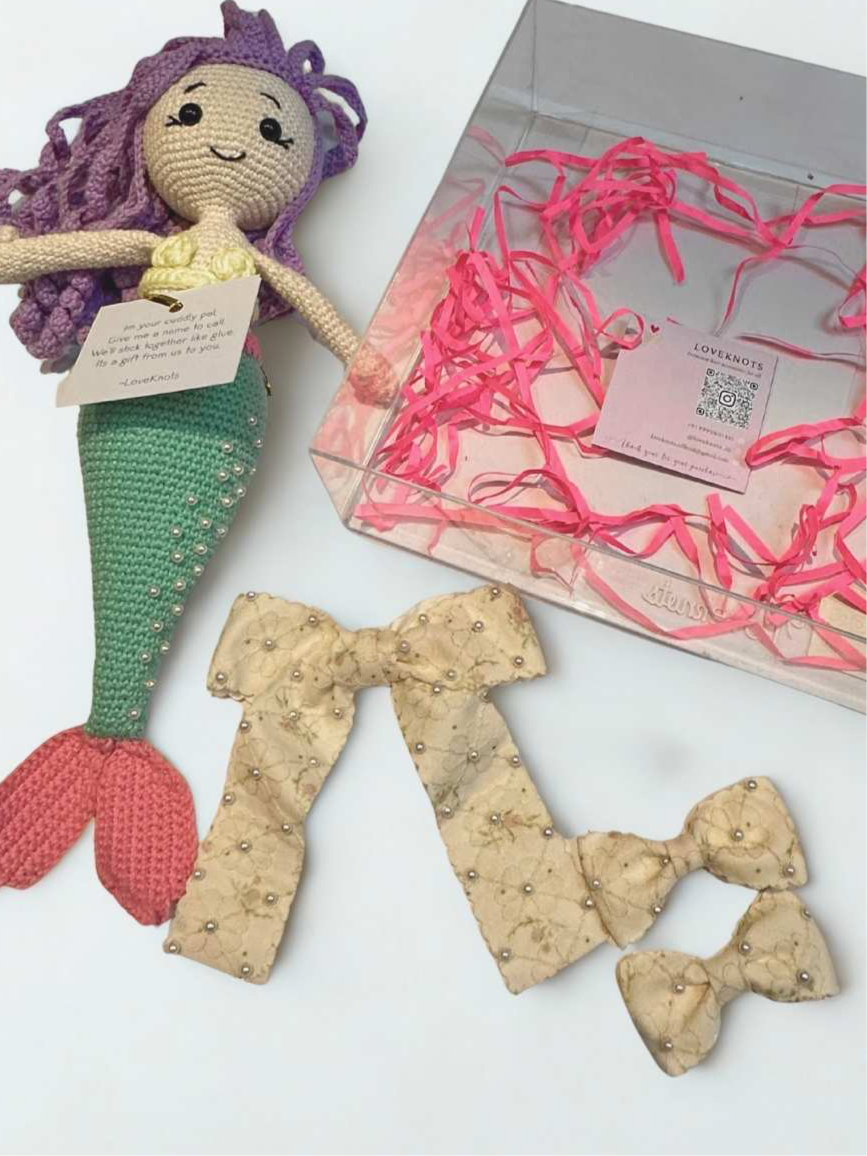 Crocheted mermaid doll with a bow and packaging on a white background