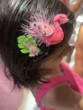 Close-up of a child's hair with flamingo clip and feathers and tropical leaf.