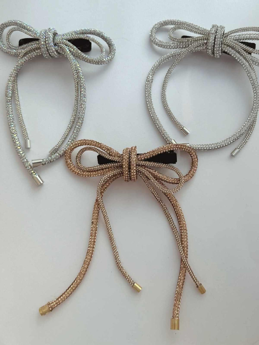 Three party wear crystal hair bows in three colors on a light background
