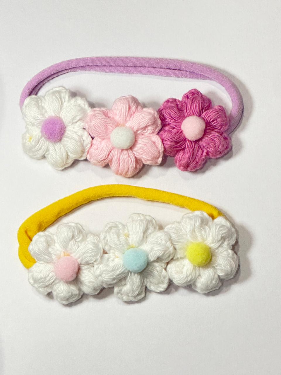Two crochet flower headbands with floral designs on baby band on a white background