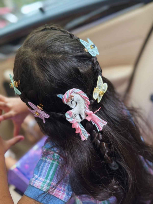 Close-up of a child's hair with unicorn bliss and butterfly clips, sitting in a car.