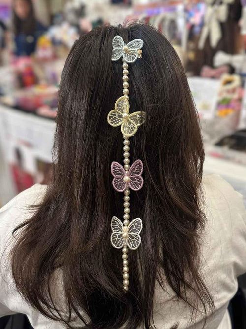 Person with decorative prandi hair accessories featuring butterflies and beads in a store setting