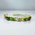 Decorative green headband with colorful gemstones on a white background