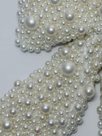 Close-up of a white pearls bow on a light gray background