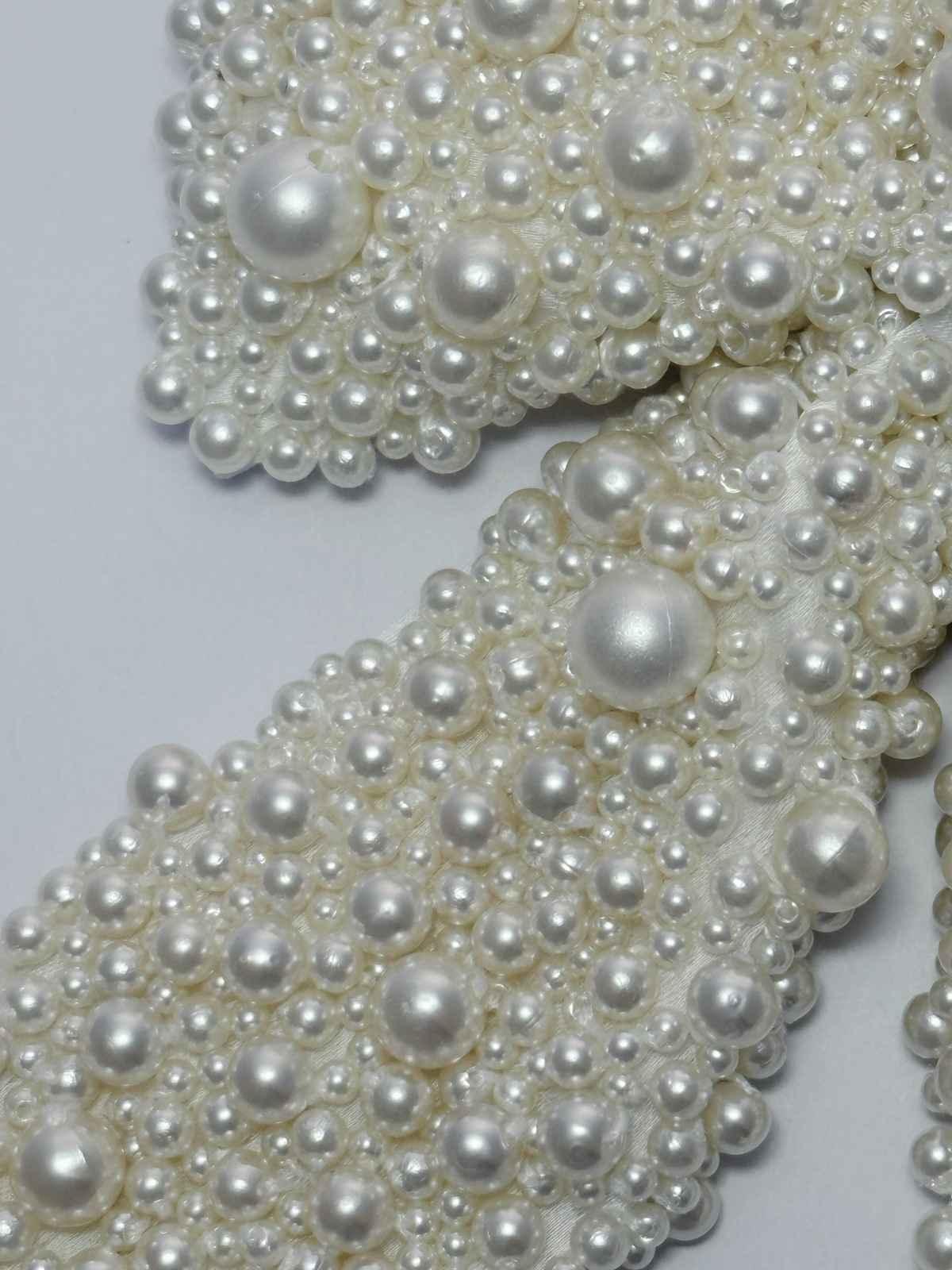 Close-up of a white pearls bow on a light gray background