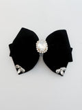 Black bow hair clip with rhinestone center on a light gray background