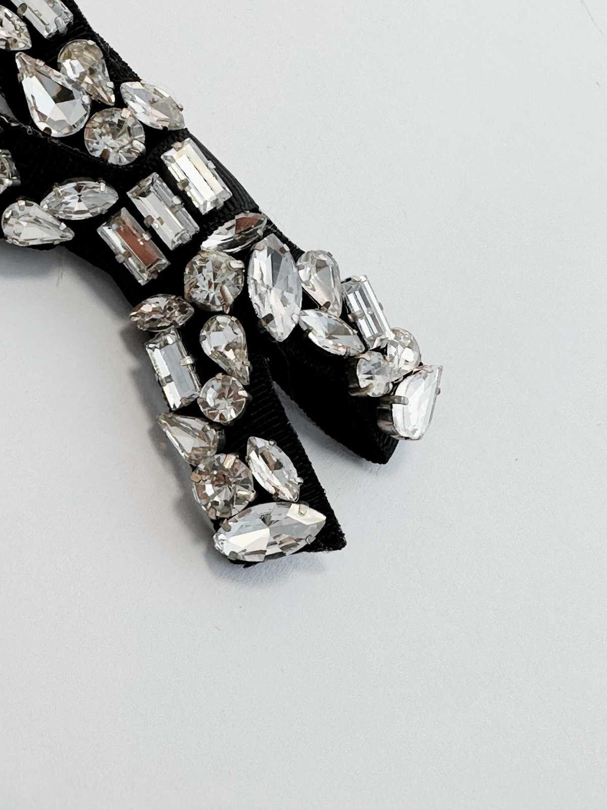 Black bow tie with crystal embellishments on a light gray background