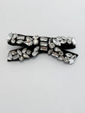 Black bow tie with crystal embellishments on a light gray background