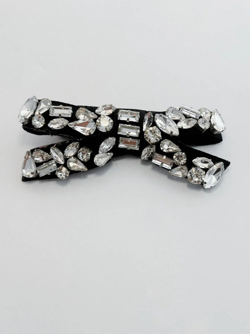 Black bow tie with crystal embellishments on a light gray background