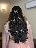 pawn behl with long, wavy hair styled with crystal bows, wearing a pink and gold traditional outfit.